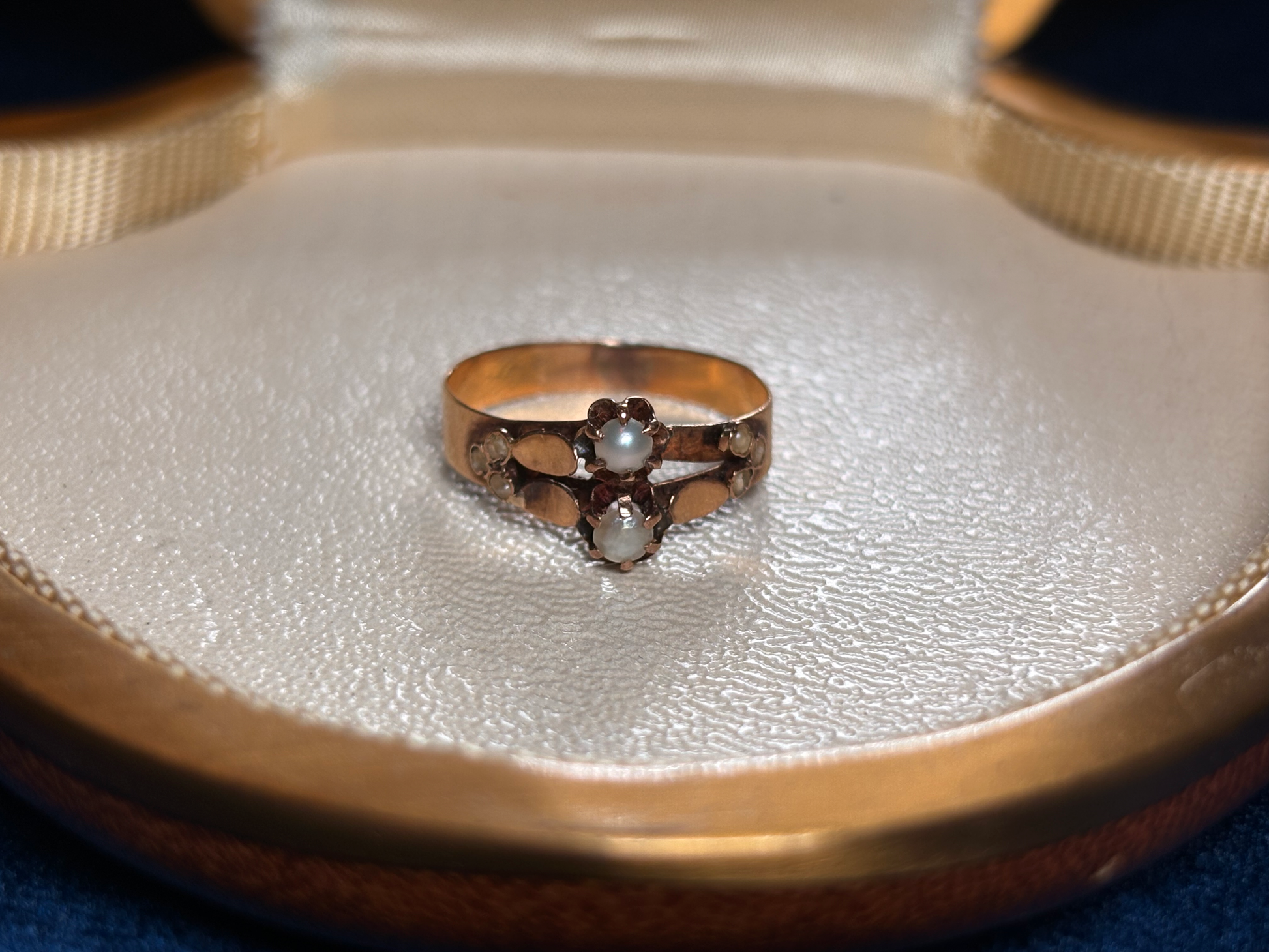 Gold ring with a central diamond and smaller stones in an open jewelry box.
