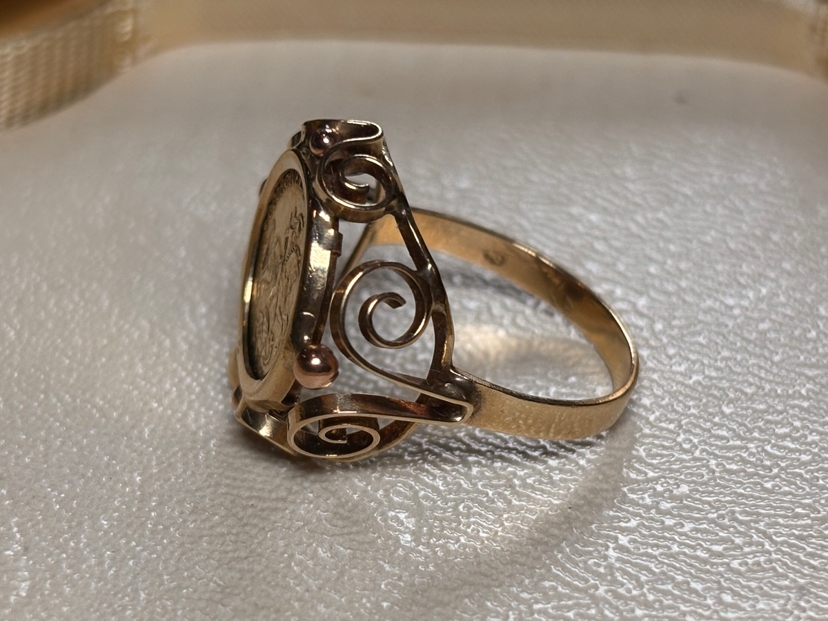 Gold ring with intricate design on a textured surface