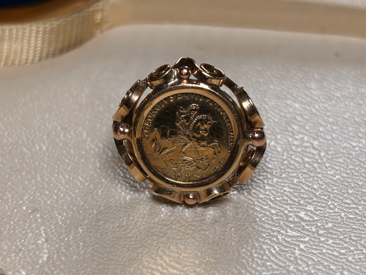 Gold ring with a coin inset on a textured surface