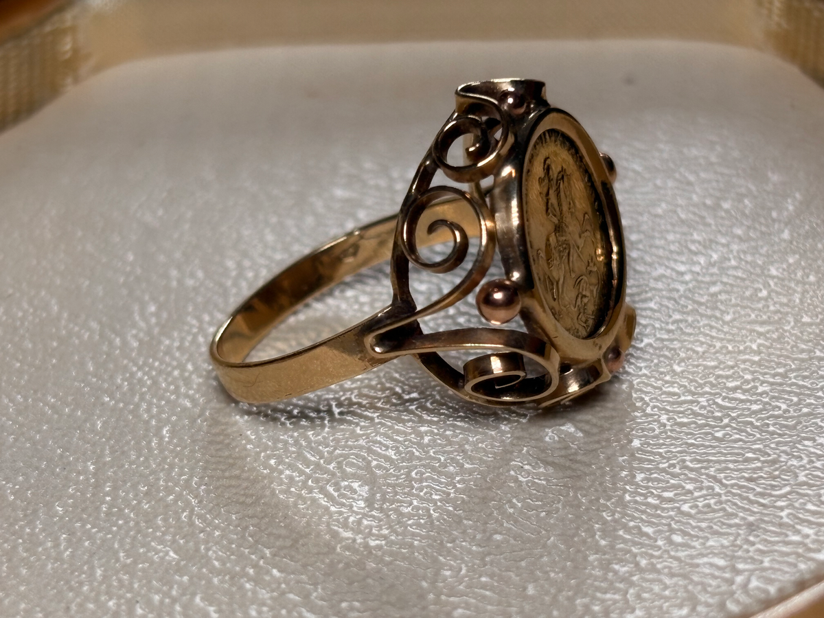 Gold ring with intricate design on a textured surface