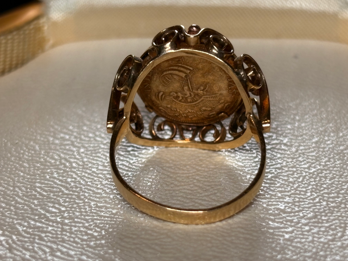 Gold ring with a coin design on a textured surface
